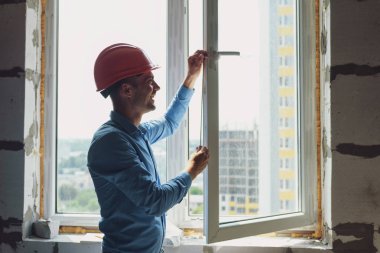 İnşaat alanındaki pencere kurulumunda çalışan erkek sanayi işçisi
