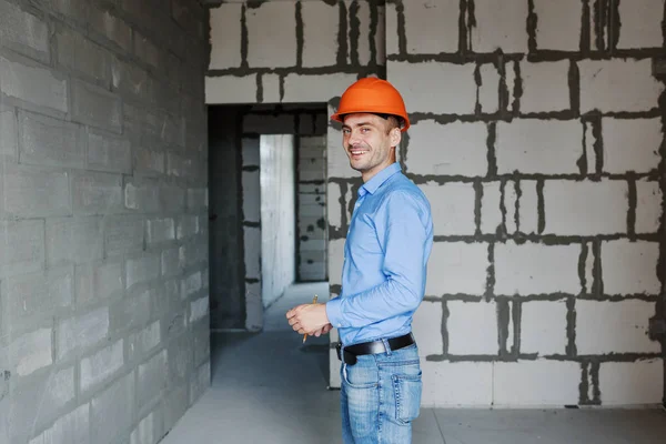Satisfied construction worker foreman measures a tape measure of a wall parameter in a house under construction. Inspects repair readiness and accuracy of work performed