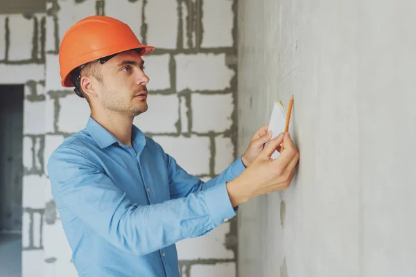 Construction supervisor writes on notebook near the wall. Handsome foreman taking notes in clipboard. Construction inspector checking new object