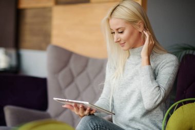 Okuma kavramı. Tablet ve içme kahve kullanan genç sarışın kadın. Rahat kafede dinlendirici, sandalyeye otur