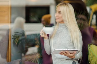 Kafedeki kadına pencerenin oturur ve zevk ile kahve içer