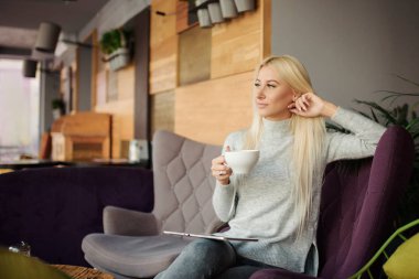 Kafedeki kadına pencerenin oturur ve zevk ile kahve içer