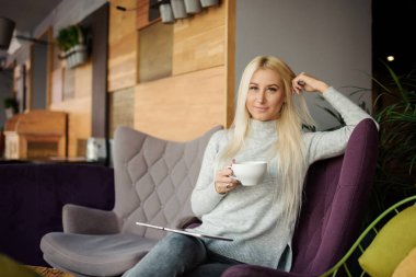 Kafedeki kadına pencerenin oturur ve zevk ile kahve içer