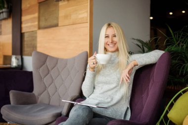 Kafedeki kadına pencerenin oturur ve zevk ile kahve içer