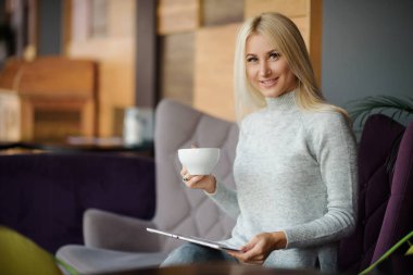 Kafedeki kadına pencerenin oturur ve zevk ile kahve içer