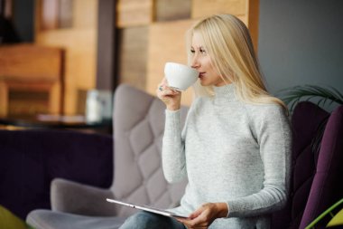 Kafedeki kadına pencerenin oturur ve zevk ile kahve içer