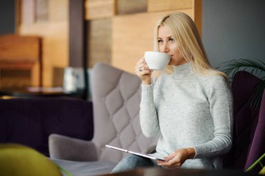 Kafedeki kadına pencerenin oturur ve zevk ile kahve içer