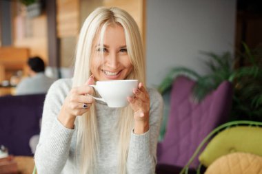 Neşeli mutlu sarışın kadın sabah kahve içme ve gülümseyen Cafe 