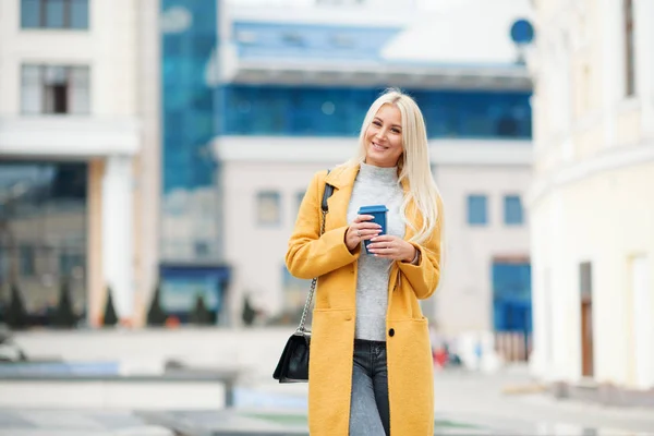 Kaffee Unterwegs Schöne Junge Blonde Frau Leuchtend Gelbem Mantel Kaffeetasse — Stockfoto