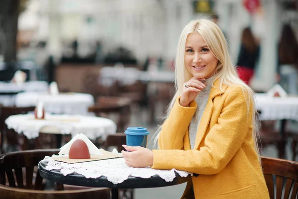 Una Joven Rubia Con Abrigo Amarillo Brillante Sienta Café Calle —  Fotos de Stock