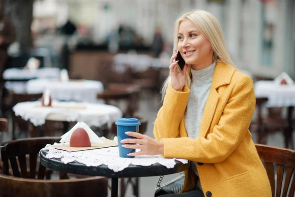 Una Joven Rubia Con Abrigo Amarillo Brillante Sienta Café Calle —  Fotos de Stock