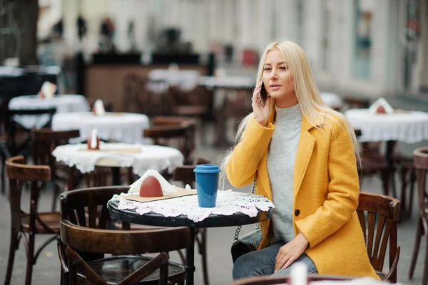 Una Joven Rubia Con Abrigo Amarillo Brillante Sienta Café Calle — Foto de Stock