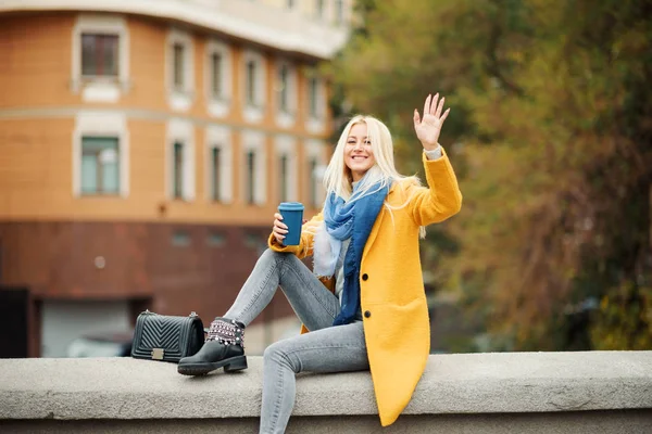 노란색 코트에서 여자가 커피를 하고있다 거리에 여자의 초상화 라이프 스타일 — 스톡 사진