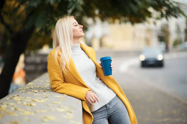 노란색 코트에서 여자가 커피를 하고있다 거리에 여자의 초상화 라이프 스타일 — 스톡 사진