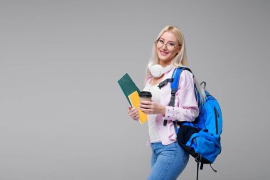 Gülümseyen genç kız öğrencinin sırt çantası içme ile kahve, kulaklık. Başlangıç, serbest meslek. Öğrenme yabancı dil online, sınava hazırlık