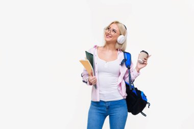 Gülümseyen genç kız öğrencinin sırt çantası içme ile kahve, kulaklık. Başlangıç, serbest meslek. Öğrenme yabancı dil online, sınava hazırlık