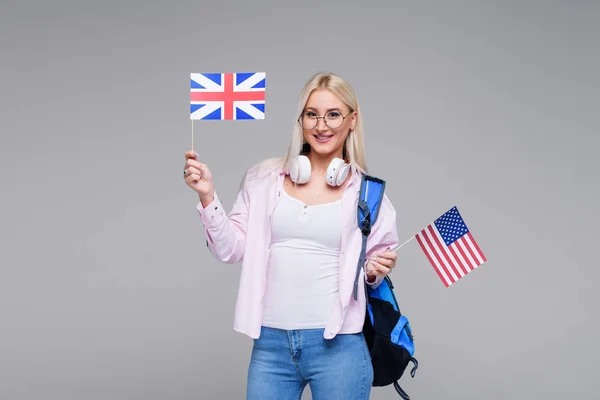 Education, foreign language translator, english, student - smiling blond woman in headphones holding American and British flags. Distance learning