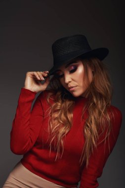 Harika beyaz kadın model parlak makyaj enerji koyu arka plan üzerinde ifade ile portresi. Şık siyah şapkalı güzel kıvırcık kadın