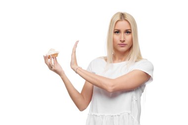 Diyet. Diyet kavramı. Sağlıklı gıda. Genç Sarışın kadın beyaz t-shirt hows lezzetli bir pasta eller durdurun. Beyaz arka plan üzerinde izole