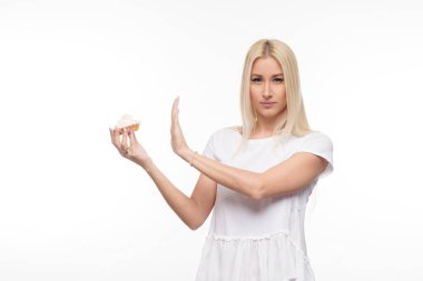 Diyet. Diyet kavramı. Sağlıklı gıda. Genç Sarışın kadın beyaz t-shirt hows lezzetli bir pasta eller durdurun. Beyaz arka plan üzerinde izole