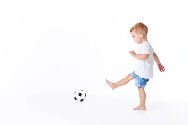 Küçük sevimli oğlu 3 yaşında, futbol tribünleri dolduran beyaz t-shirt futbol topuyla oynayan beyaz arka plan üzerinde izole. yaşam tarzı kavramı. Metin için yer kopyalayın