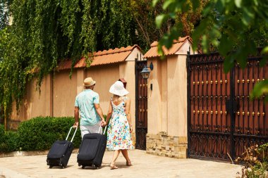 Mutlu çift tatilde bavullarıyla otele gidiyor. 