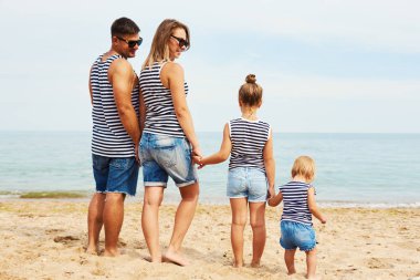 Sahilde mutlu bir aile. İnsanlar yaz tatile eğleniyor. Baba, anne ve çocuk mavi deniz ve gökyüzü arka plan karşı. Tatil seyahat kavramı. Arkadan görünüm 