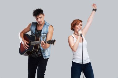 Müzik sanatçı şarkı ve akustik gitar çalmak. Çağdaş müzik grubu. Gri arka plan üzerinde izole. Kadın mikrofon ile yüksek sesle şarkı 