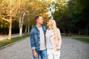 Mutlu genç çift sarılma ve açık havada gülüyor aşık. Güneşli parkta yürüyüş