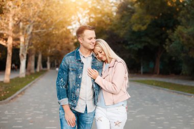 Mutlu genç çift sarılma ve açık havada gülüyor aşık. Güneşli parkta yürüyüş