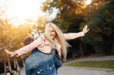 Happy loving couple. Happy young man piggybacking his girlfriend while keeping arms outstretched