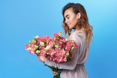 Buket üzerinde mavi arka plan izole renkli bahar çiçek tutan genç mutlu gülümseyen Kızıl saçlı kadın. 8 Mart kadınlar günü veya doğum günü, pembe Gül, Festival buket saygı