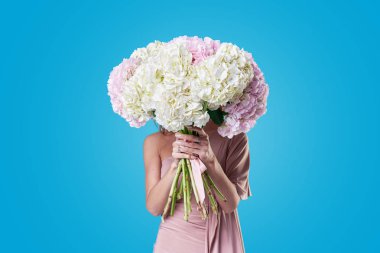 Uzun kahverengi saçlı olması ile neşeli genç bayan üzerinde mavi arka plan izole kadınlar günü buket bahar çiçek almak için heyecanlı