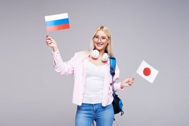 Eğitim, yabancı dil çevirmen, İngilizce, öğrenci - gülümseyen Rusya ve Japonya bayrak tutan Kulaklığımda sarışın kadın. Uzaktan eğitim
