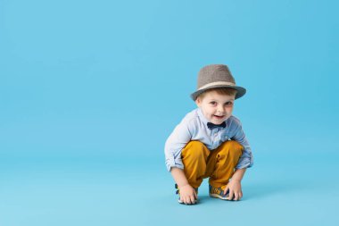 Üzerinde mavi arka plan izole mutlu neşeli küçük çocuk portresi. Yürümeye başlayan çocuk şapka ve şık gülümseyen uygun ve bir iyi eğlenceler 