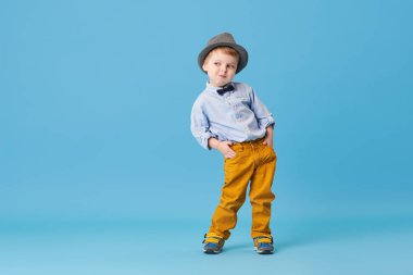 Üzerinde mavi arka plan izole mutlu neşeli küçük çocuk portresi. Yürümeye başlayan çocuk şapka ve şık gülümseyen uygun ve bir iyi eğlenceler 