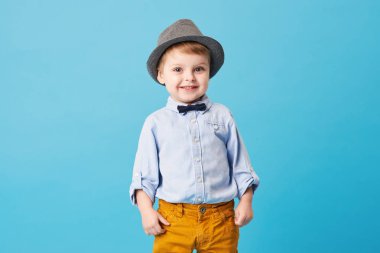 Üzerinde mavi arka plan izole mutlu neşeli küçük çocuk portresi. Yürümeye başlayan çocuk şapka ve şık gülümseyen uygun ve bir iyi eğlenceler 