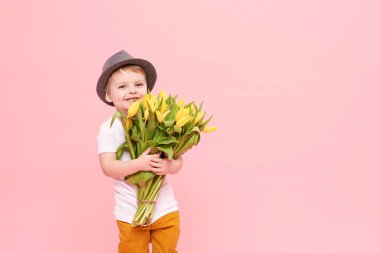 Bahar çiçek buketi pembe üzerinde izole kamera bakıyor tatlı gülümseyen hamile. Anne için hediye olarak Sarı laleler tutan şapkalı küçük yürümeye başlayan çocuk