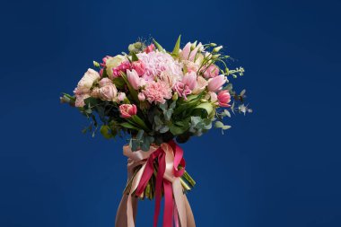 Üzerinde mavi arka plan bahar buket gözümün önünde tutan genç kadın portresi