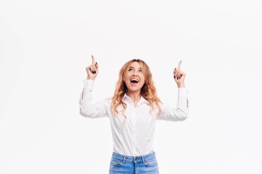 Genel olarak kameraya gülümseyen, parmakları işaret, ilginç ve heyecan verici bir şey kopya alanı metin veya reklam içeriği ile beyaz arka plan üzerinde gösterilen mutlu sürpriz genç kadın