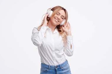 Kablosuz bağlantı. Genç güzel zevk kadın portre kulaklık ile beyaz arka plan dinleme müzik üzerinde izole poz. 