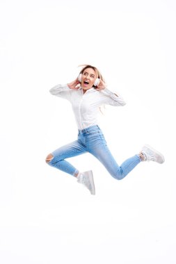 Muhteşem redhead Bayan kulaklıkta radyo müzik dinleme ve yüksek atlama. Rahat giysiler ve kulaklıklar beyaz arka planda sallayarak saç ile dans Charming kız. Tam uzunluklu portre