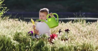 yürümeye başlayan çocuk maça ve sulama ile çiçekler arasında oturur olabilir