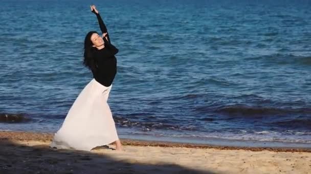 快乐长发的女人在雪纺裙子挥舞在风摆姿势在沙滩上对滚动的深蓝色波浪慢动作 — 图库视频影像