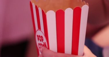 erkek el lezzetli snack ile büyük çizgili kağıt kutusu tutar ve patlamış mısır aşırı yakın görünümü yiyor