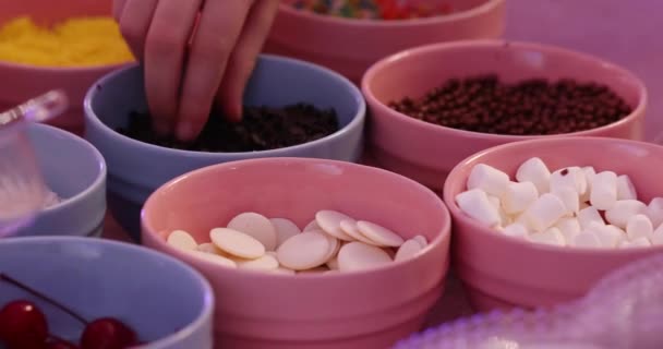 人々の手は おいしい焼きドーナツ極端な近いビューを飾るために小さなピンクのボウルから速くおいしい調味料を取ります — ストック動画