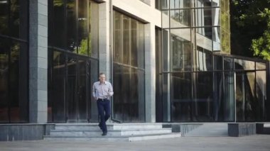 çizgili gömlek yakışıklı adam güneşli şehir sokakta mutlu dans modern ofis binası bırakır