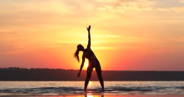 deniz suyunda spor standları ince bayan siluet nefes kesen günbatımı arka görünümüne karşı mükemmel bir vücut uzanır