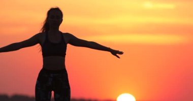 sportif kadın silueti nefes yoga teknikleri turuncu gökyüzü closeup beyaz güneş diskine karşı kollarını germe uygulamaları