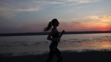 at kuyruklu ince kadın akşam güneş ışığı yakın görünümü yavaş hareket ile harika gökyüzüne karşı deniz plajında çalışan sahiptir